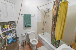 Bathroom featuring tile patterned floors, shower / bath combination with curtain, and toilet