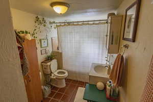 Bathroom featuring tile patterned floors, vanity, tile walls, toilet, and curtained shower