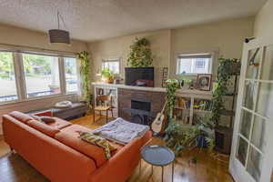 Living room with wood-type flooring, a healthy amount of sunlight, and a brick fireplace