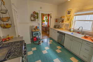 Kitchen with white cabinetry, stainless steel dishwasher, range with gas cooktop, and sink