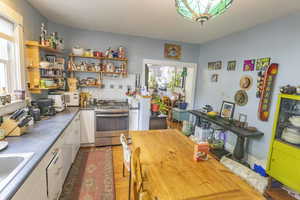 Kitchen featuring sink, white cabinetry, backsplash, and gas range