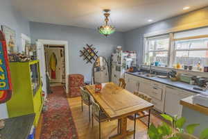 Kitchen with light wood-type flooring, sink, decorative light fixtures, white fridge, and white cabinetry