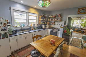 Kitchen with sink, white cabinets, white appliances, and light wood-type flooring