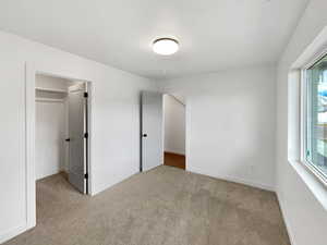 Unfurnished bedroom featuring a closet and light colored carpet