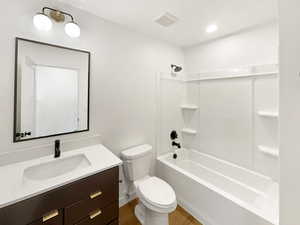 Full bathroom with wood-type flooring, vanity, toilet, and tub / shower combination