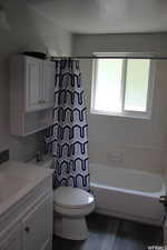 Full bathroom featuring vanity, shower / bath combination with curtain, toilet, and wood-type flooring