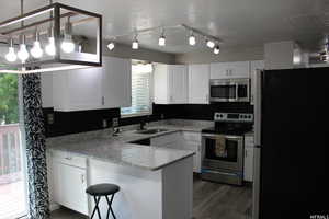 Kitchen with sink, white cabinetry, and stainless steel appliances