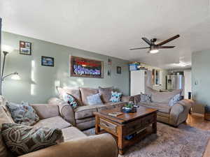 Living room with ceiling fan, hardwood / wood-style floors, and a textured ceiling