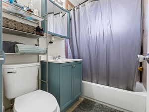 Full bathroom with tile patterned floors, shower / bath combination with curtain, toilet, and vanity