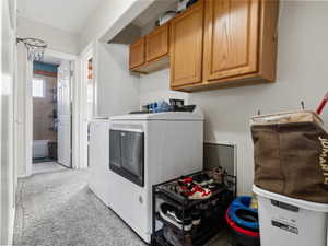 Laundry area featuring cabinets, light tile patterned floors, and washing machine and dryer