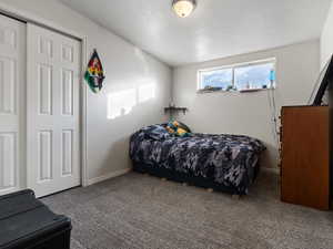 Bedroom with a closet, dark carpet, and a textured ceiling