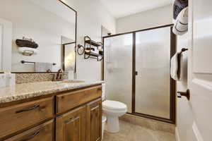 Bathroom with tile patterned flooring, vanity, toilet, and a shower with door