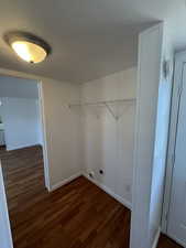 Laundry area featuring dark wood-type flooring, a textured ceiling, and hookup for an electric dryer