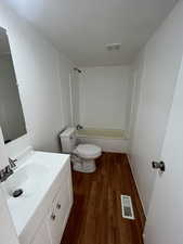 Full bathroom with bathing tub / shower combination, hardwood / wood-style floors, vanity, and toilet