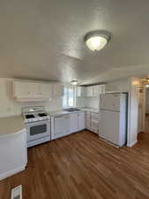 Kitchen featuring sink, white cabinets, wood-type flooring, and white appliances