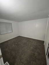 Spare room featuring dark colored carpet