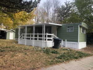 View of front of home featuring a porch and a storage shed