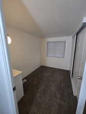 Unfurnished bedroom featuring dark colored carpet, a textured ceiling, and a closet