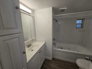 Full bathroom with shower / bath combination, a textured ceiling, toilet, wood-type flooring, and vanity