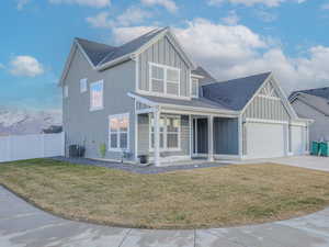 View of front of home with central AC, a front yard, and a garage