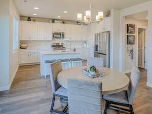 Dining room with sink, a notable chandelier, and light hardwood / wood-style flooring