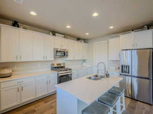 Kitchen featuring white cabinets, sink, stainless steel appliances, and hardwood / wood-style floors