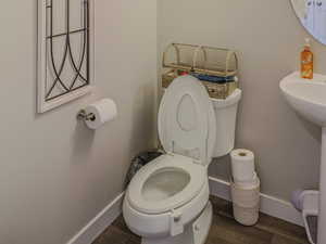 Bathroom with toilet, wood-type flooring, and a textured ceiling