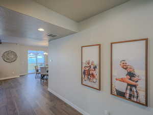 Hall with a textured ceiling, dark hardwood / wood-style flooring, and an inviting chandelier