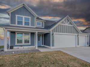 View of front of house featuring a porch, a garage, and a lawn