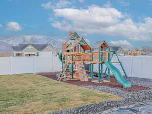 View of playground with a mountain view and a lawn