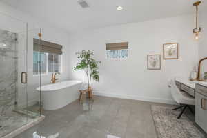 Bathroom featuring shower with separate bathtub and vanity