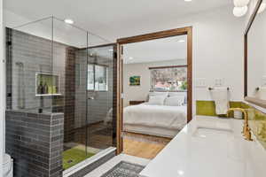 Primary Bathroom featuring vanity, a shower with shower door, and hardwood / wood-style flooring