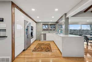 Kitchen with white cabinetry, light hardwood / wood-style floors, and appliances with stainless steel finishes