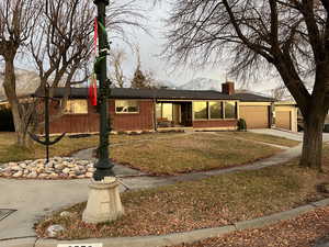 Single story home with a front yard and a garage at sunset