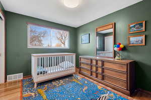 Bedroom with hardwood / wood-style floors and a crib