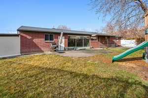 Back of property featuring a playground, a yard, and a patio