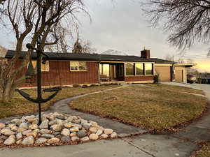 View of front of property with a yard and a garage at sunset