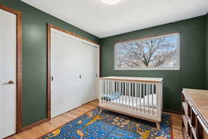 Bedroom with a closet, a nursery area, and light wood-type flooring