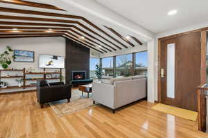 Living room featuring vaulted ceiling with beams, a large fireplace, and light hardwood / wood-style floors