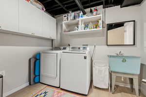 Laundry room featuring cabinets, light hardwood / wood-style floors, washer and clothes dryer, and sink