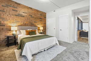 Carpeted bedroom with brick wall