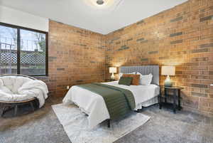 Bedroom with carpet and brick wall