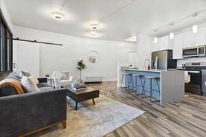 Living room featuring a barn door, sink, and light hardwood / wood-style floors