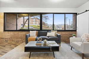 Living room featuring a barn door, brick wall, and wood-type flooring