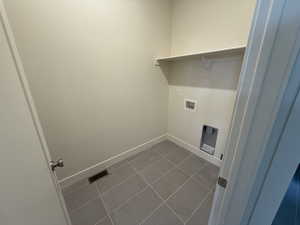 Clothes washing area with washer hookup and dark tile patterned floors.