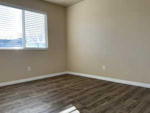 Empty room featuring dark hardwood / wood-style flooring and a healthy amount of sunlight