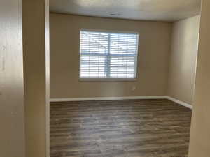 Spare room featuring dark wood-type flooring and a textured ceiling