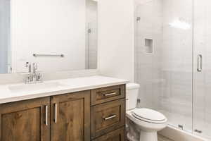 Bathroom with a shower with door, vanity, and toilet