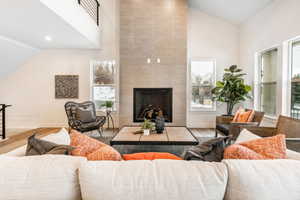 Living room with a fireplace, high vaulted ceiling, and light hardwood / wood-style floors