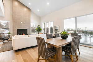 Dining area with a tile fireplace, high vaulted ceiling, and light hardwood / wood-style flooring